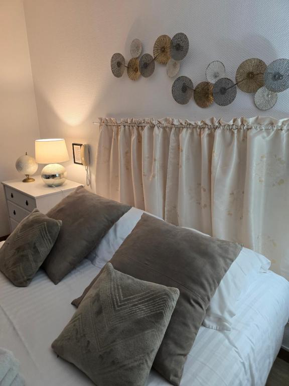 a bed with some pillows on it in a bedroom at Hôtel L'ideal le Mountbatten in Arromanches-les-Bains