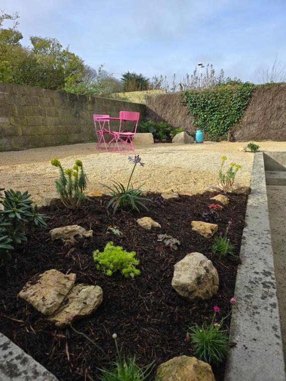 a garden with a pink chair and rocks at Hôtel L'ideal le Mountbatten in Arromanches-les-Bains