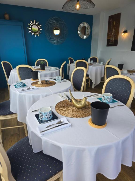 a dining room with white tables and chairs at Hôtel L'ideal le Mountbatten in Arromanches-les-Bains