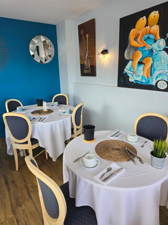 two tables in a restaurant with white tables and chairs at Hôtel L'ideal le Mountbatten in Arromanches-les-Bains