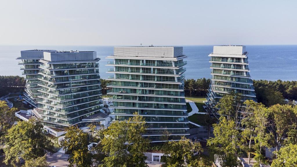 two tall buildings in front of the ocean at Wave by Baltic Home in Międzyzdroje