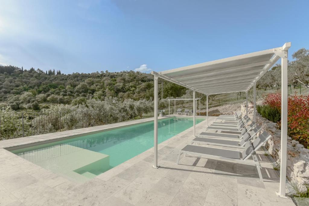 an outdoor swimming pool with a canopy and chairs at Agriturismo Il Mulino delle canutole in Magione