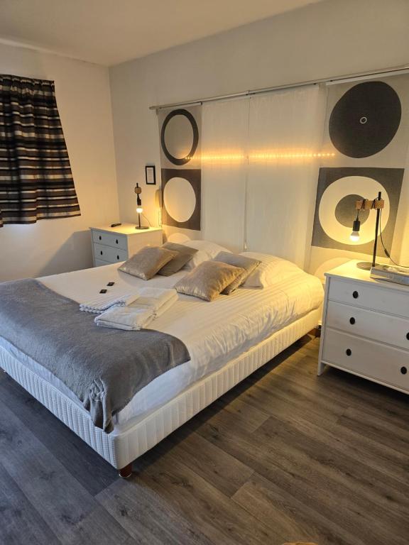 a bedroom with a large white bed with two night stands at Hôtel L'ideal le Mountbatten in Arromanches-les-Bains
