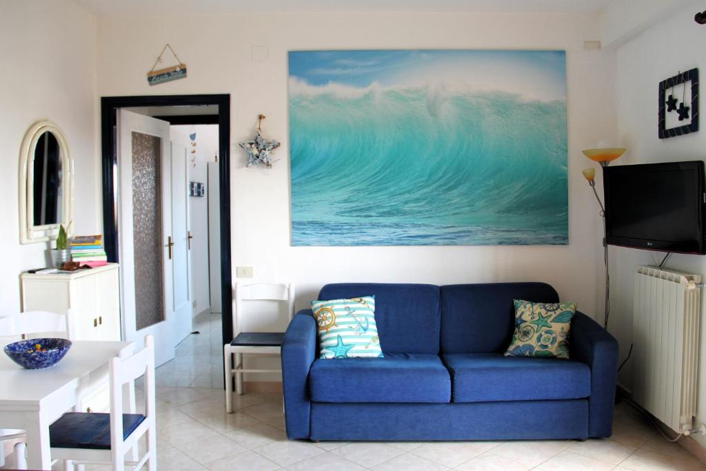 a living room with a blue couch and a painting at Casa Serendipity Sabaudia in Sabaudia