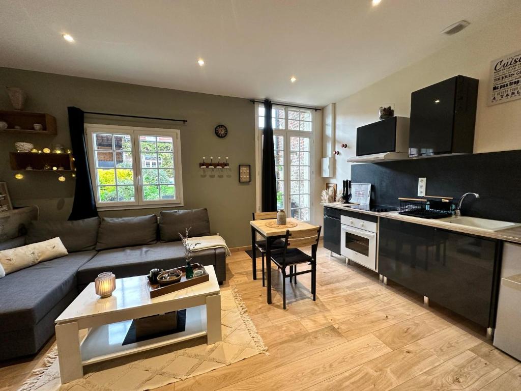 ein Wohnzimmer mit einem blauen Sofa und einer Küche in der Unterkunft gîte Cosy Green 2 in Chevincourt