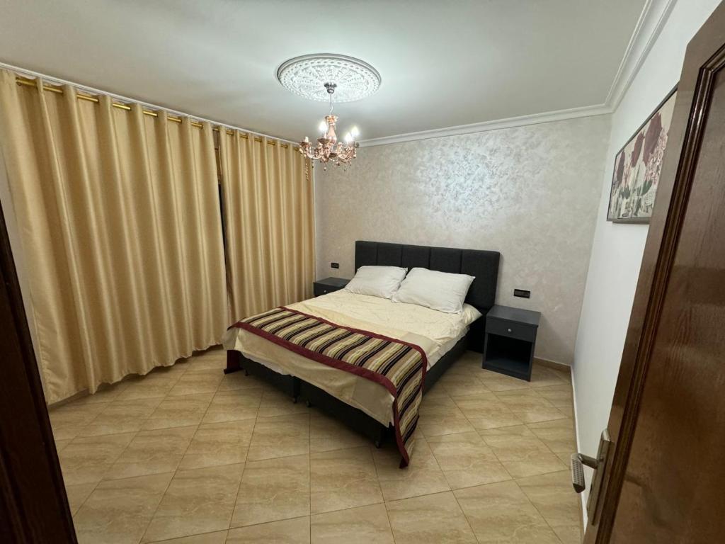 um quarto com uma cama e um lustre em Appart Hotel Excellent em Nador