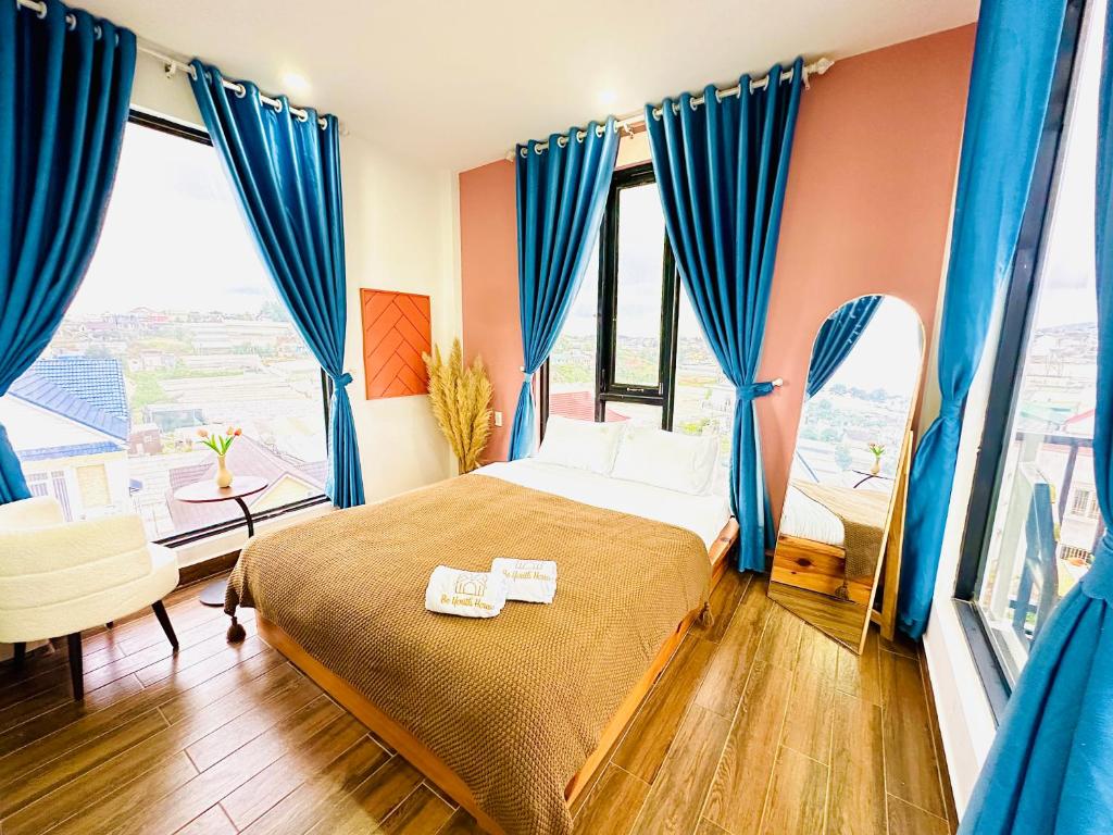 1 dormitorio con 1 cama con cortinas azules en Be Youth Villa Đà Lạt, en Da Lat