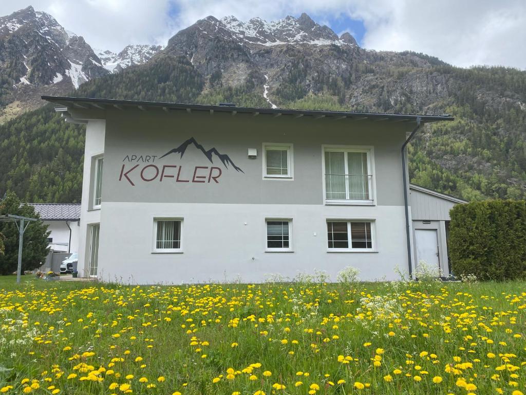 a white building in a field of flowers at Apart Kofler in Längenfeld