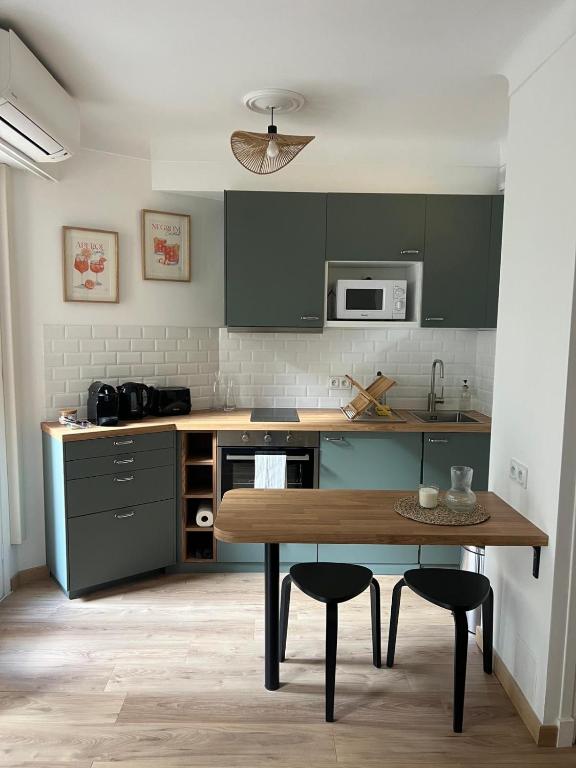 une cuisine avec des placards verts et une table en bois dans l'établissement Studio centre-ville Beaulieu-sur-Mer, à Beaulieu-sur-Mer