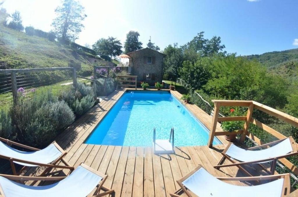 una piscina en una terraza de madera con 2 sillas en Ferienhaus mit Privatpool für 6 Personen ca 95 qm in Castelvecchio, Toskana Provinz Pistoia en Aramo