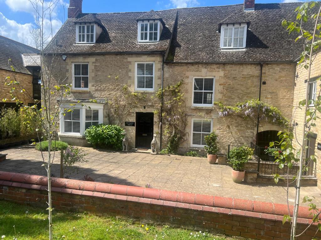 an old stone house with a cat sitting in front of it at The Rutland House South Luffenham in Oakham