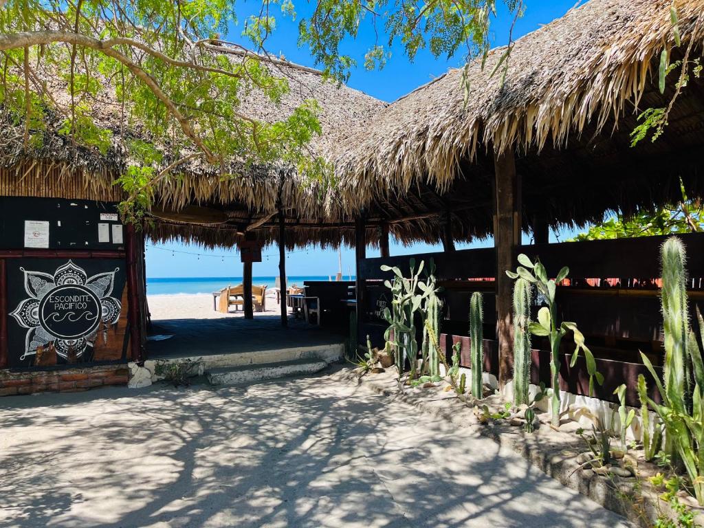 a hut on the beach with a thatched roof at Escondite Pacifico in Popoyo