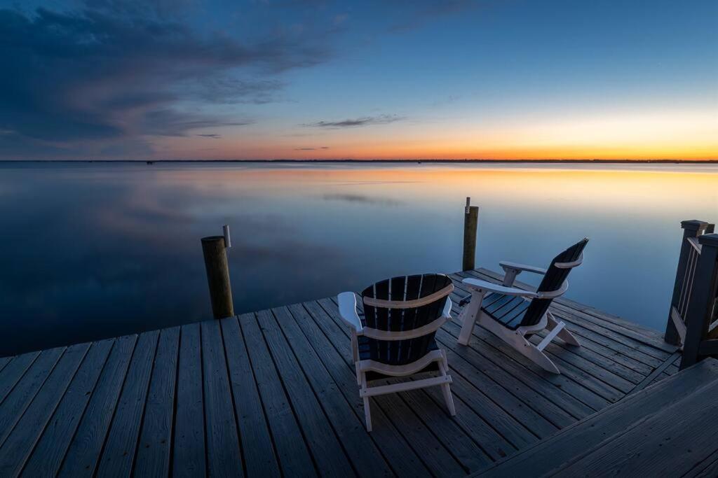 a dock with two chairs and a table on the water at Sea La Vie Beach Cottage in Virginia Beach