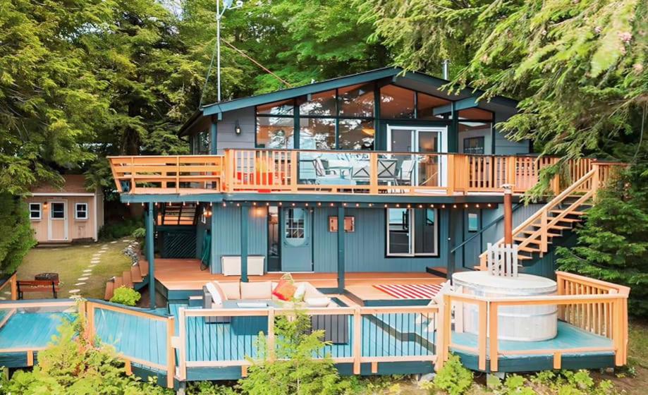 a blue house with a deck and a pool at Alpine Lake House - Waterfront on Lake Muskoka in Port Carling