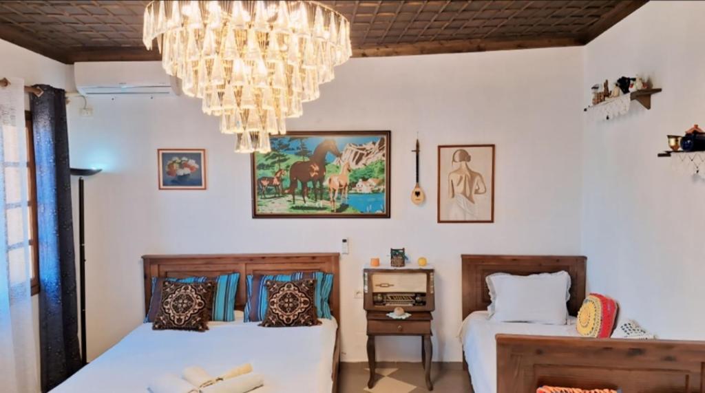 two beds in a room with a chandelier at Guesthouse Alvaro Kadiu in Berat