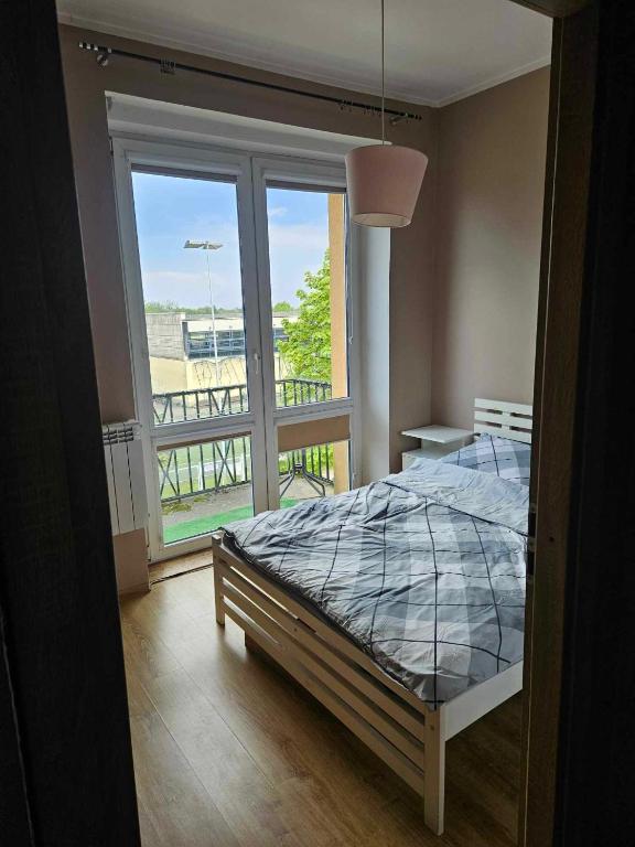 a bedroom with a bed and a large window at Apartament kamienica in Gdynia