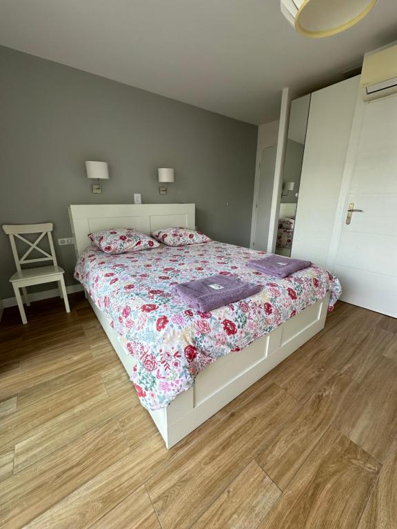 a bedroom with a bed with a floral comforter and a mirror at Villa MA&VA in Lacanau-Océan