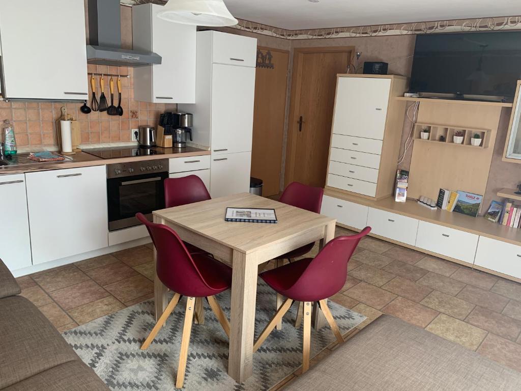 a kitchen with a wooden table and red chairs at Ferienwohnung Pölkentor in Quedlinburg