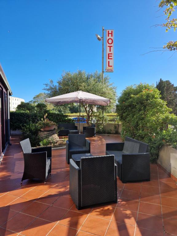 a patio with chairs and an umbrella at Hotel Mistral in Alghero