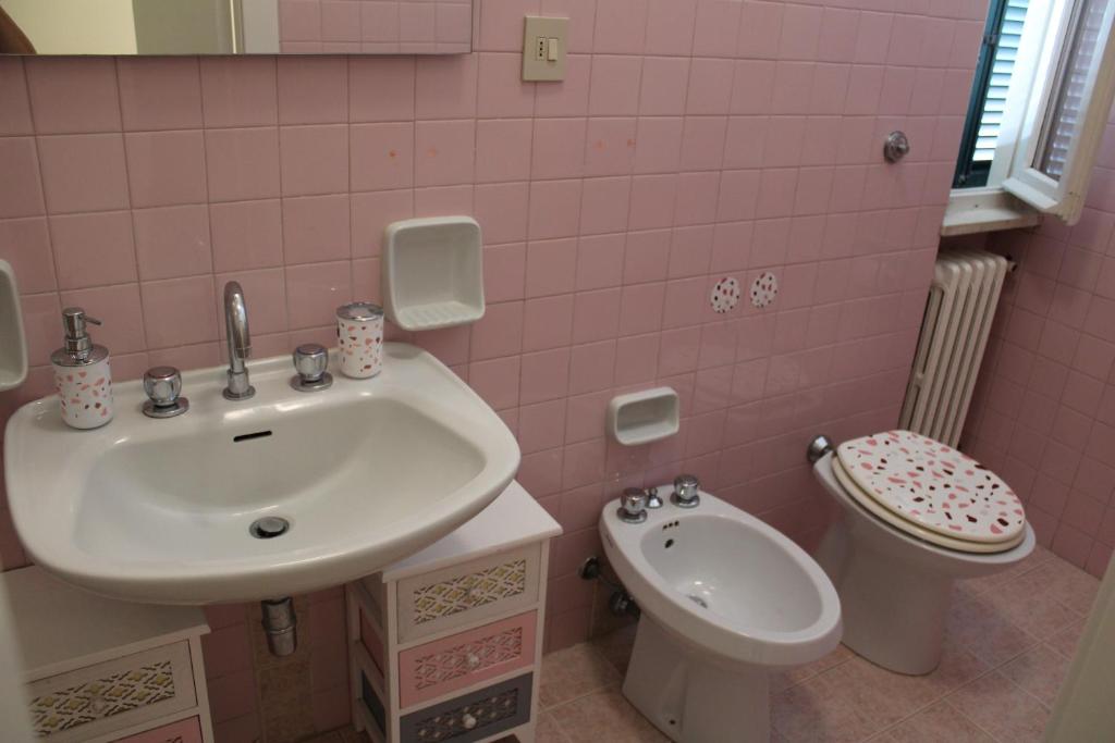 różowa łazienka z umywalką i toaletą w obiekcie Appartamenti Sirolo 60020 w mieście Sirolo