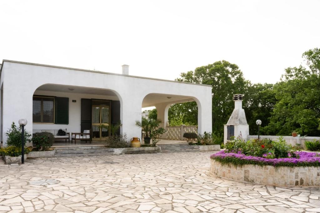 ein weißes Haus mit einer Steinterrasse und Blumen in der Unterkunft La Dimora di Helen in Monopoli