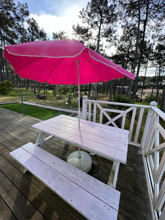 a picnic table with a pink umbrella on a deck at Villa MA&amp;VA in Lacanau-Océan