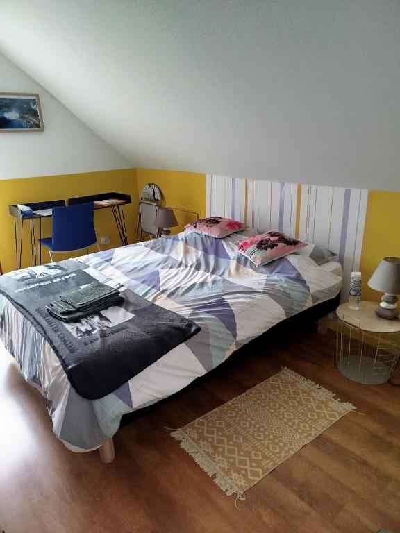 a bedroom with a large bed with a striped wall at Chambre jaune avec salle de bain collective in Cluses