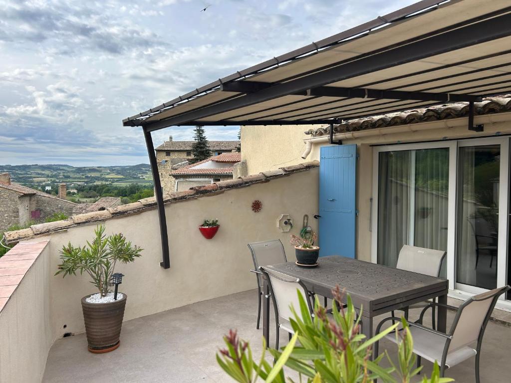 patio ze stołem i krzesłami na balkonie w obiekcie Entre couleurs et senteurs w mieście Mirabel-aux-Baronnies