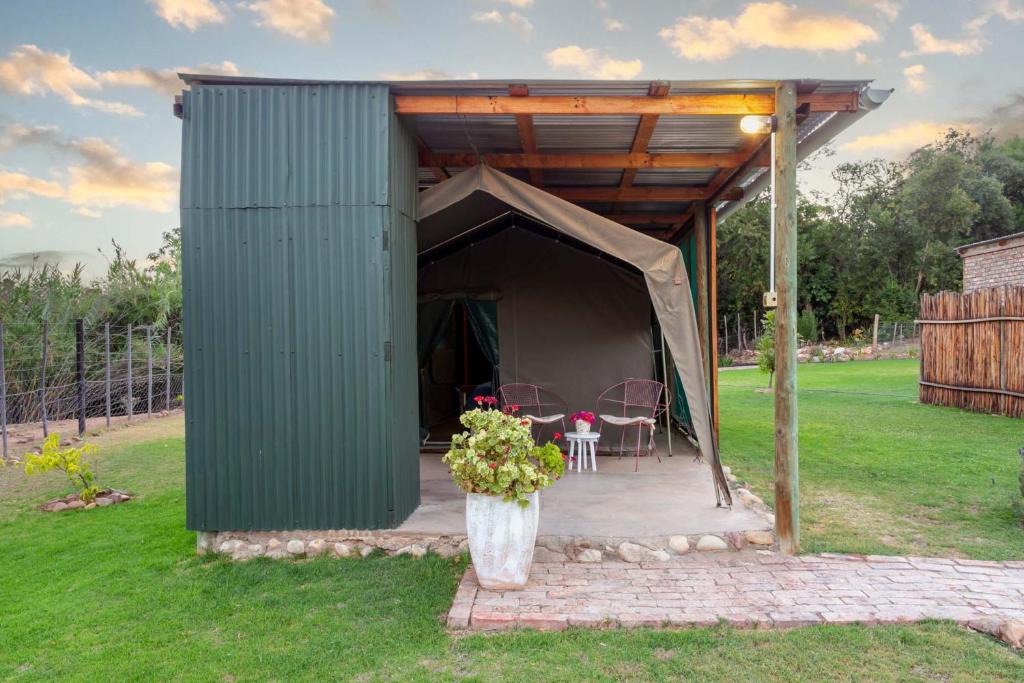 a green shed with a table and chairs in it at Schoemanshoek Glamping in Oudtshoorn