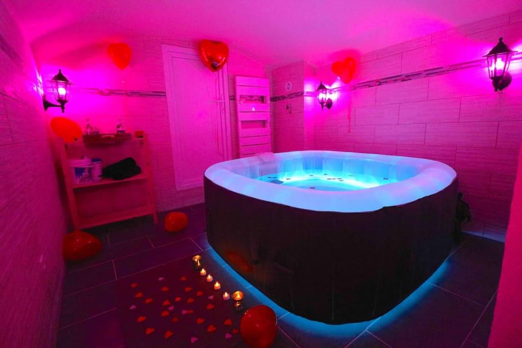 een badkamer met een groot bad met roze verlichting bij Expérience INSOLITE ! ROMANTIQUE / ESCAPE GAME in Lizy-sur-Ourcq