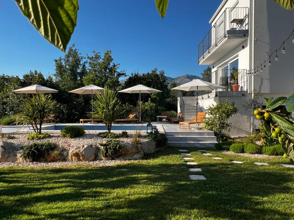 una casa con un cortile con ombrelloni di Meridiem Holiday Home in Dubrovnik region a Gruda