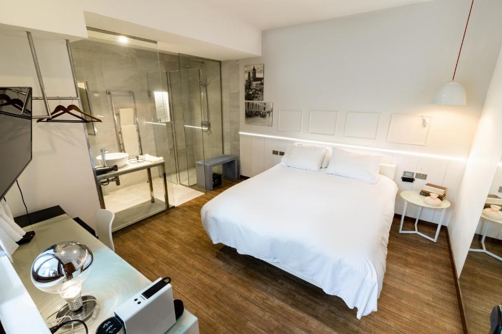 1 dormitorio con cama blanca y ducha en Cosmopolitano Hotel Boutique en Santa Cruz de la Sierra