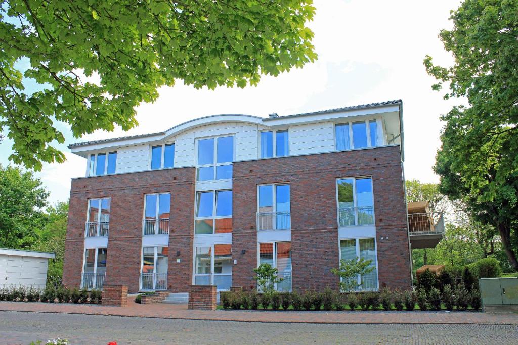 un grand bâtiment en briques avec des fenêtres bleues dans l'établissement Wohnung 10 Haus Oldenburg, à Wangerooge