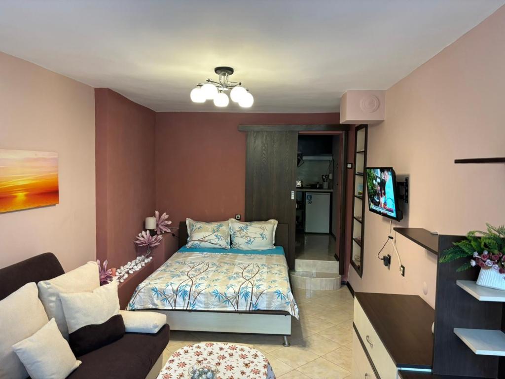 a small bedroom with a bed and a couch at Партерно Студио in Ahtopol