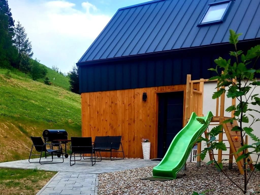 a playground with a green slide next to a building at Domek Wonkopianka in Grywałd