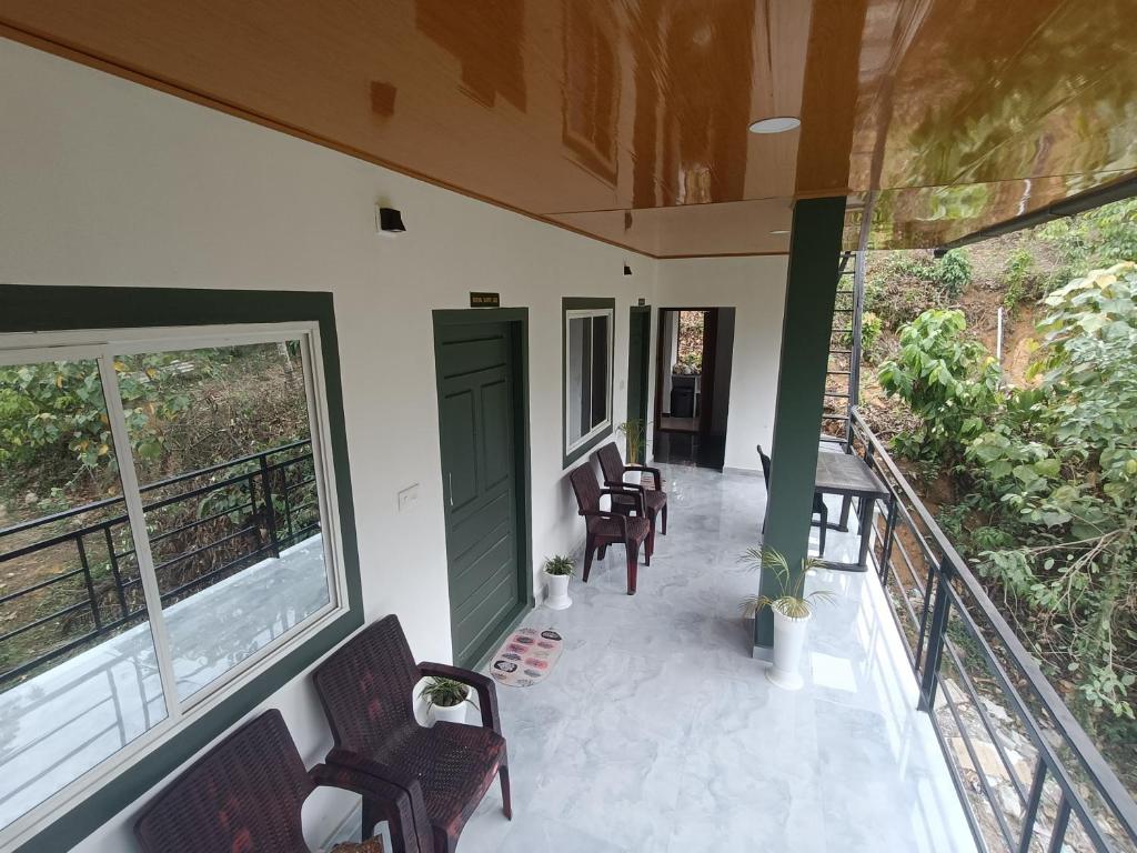 un porche de una casa con sillas y una puerta verde en Habees Residency en Chillithodu