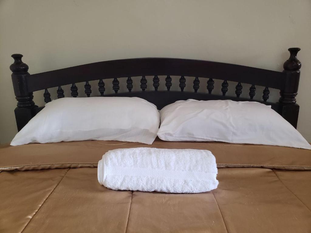 a bed with two white pillows on top of it at Sunset suite in Meru