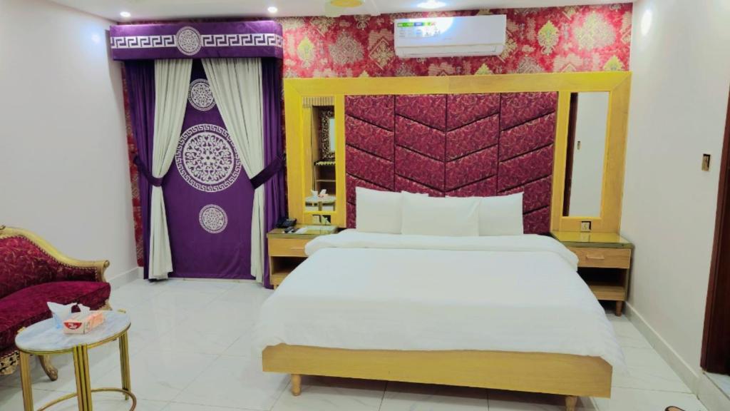a bedroom with a large bed and a purple wall at Clifton Lodge Boutique Hotel in Karachi