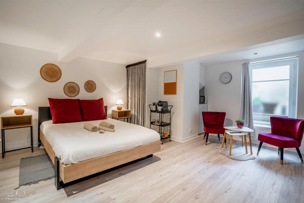 ein Schlafzimmer mit einem großen Bett und zwei roten Stühlen in der Unterkunft La cabane du pêcheur - Nantes - Bord de Loire in Rezé