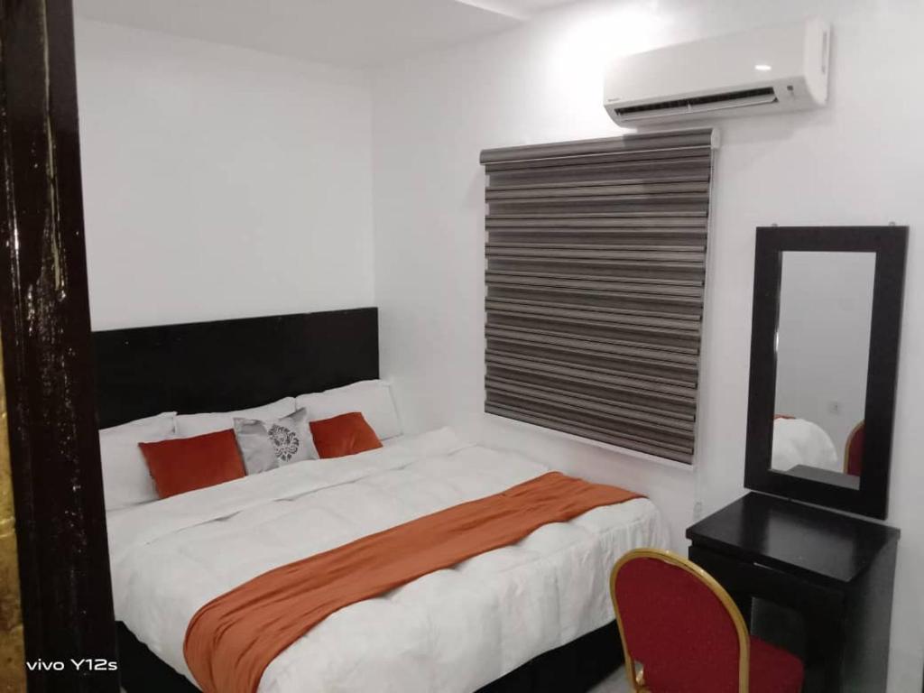 Blue Moon Hotel Victoria Island في لاغوس: غرفة نوم بسرير وخزانة ومرآة