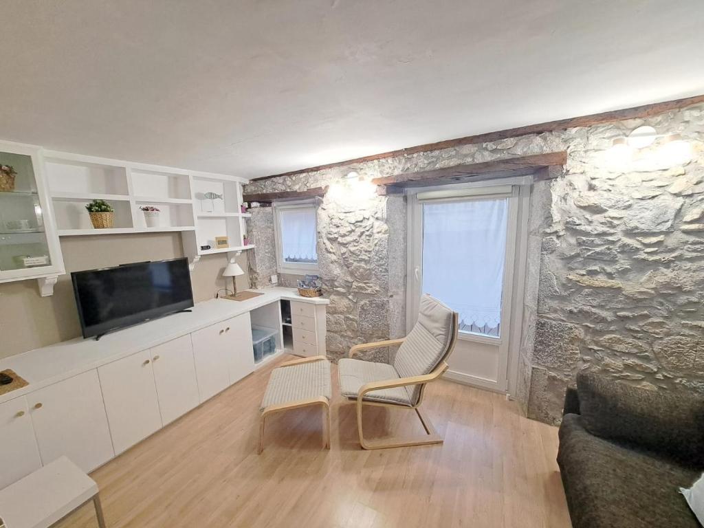 salon z kamienną ścianą, kanapą i krzesłem w obiekcie Apartamento en el Casco Viejo. Itsasargi w mieście Lekeitio