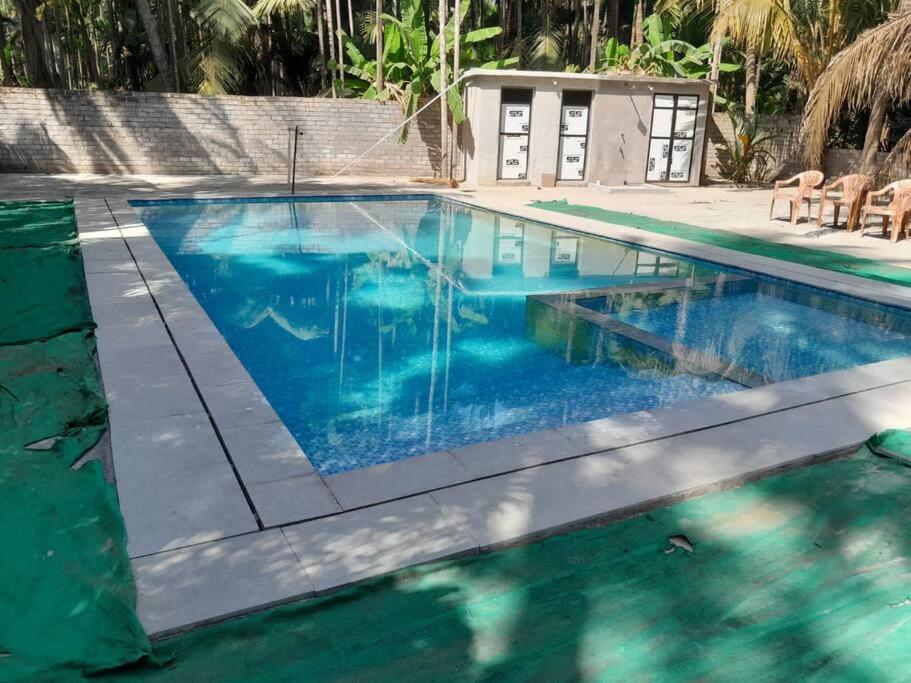 una piscina de agua azul en un complejo en Aanandamay Homestay en Revadanda