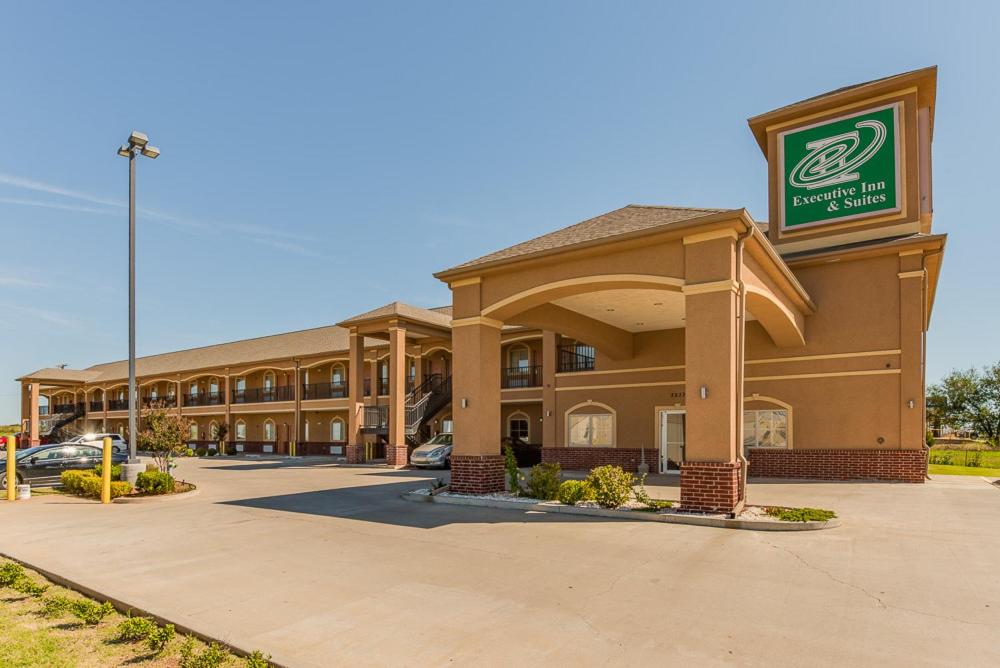 a front view of a hotel with a parking lot at Executive Inn & Suites Cushing in Cushing