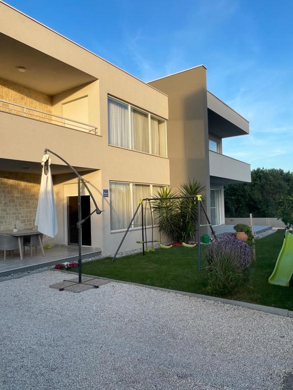 une maison avec une cour dotée d'un parasol et d'une aire de jeux dans l'établissement Luxury Apartment Sofia, à Bibinje