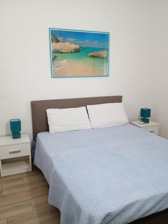 sypialnia z łóżkiem z niebieskim kocem i oceanem w obiekcie Villetta Bouganville w mieście San Teodoro
