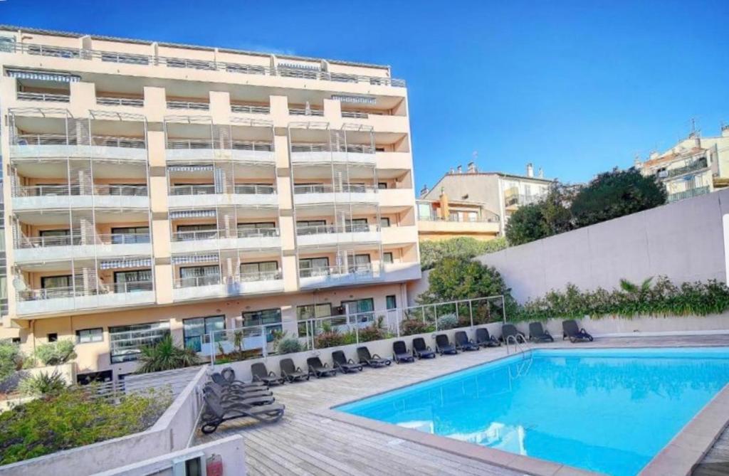 un hôtel avec une piscine et un bâtiment dans l'établissement Studio piscine proche plage et palais des festivals cannes banane, à Cannes