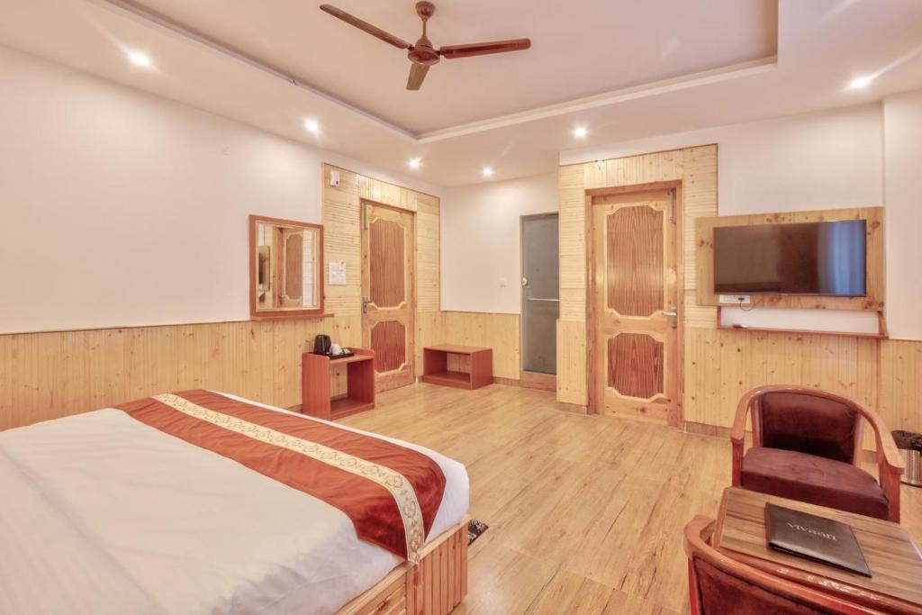 Vivaan stays في Shamshi: غرفة نوم بسرير وتلفزيون بشاشة مسطحة