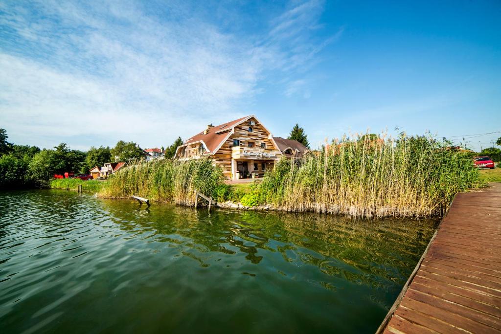 a house sitting on the edge of a lake at Pensjonat U Jacka in Olsztyn