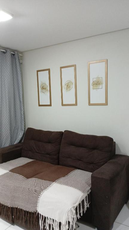 um sofá numa sala de estar com três fotografias na parede em Apartamento Villa Giovanne em João Pessoa