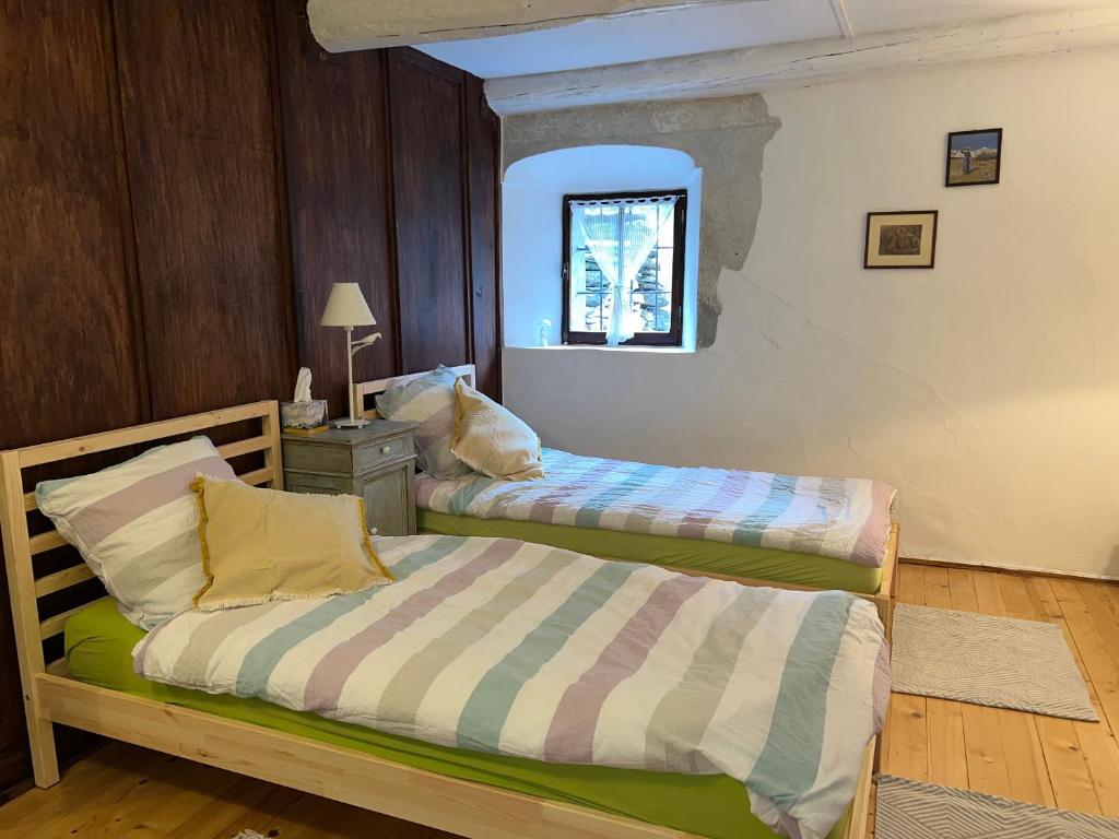 1 dormitorio con 2 camas y ventana en Rusticus1706, en Lavertezzo